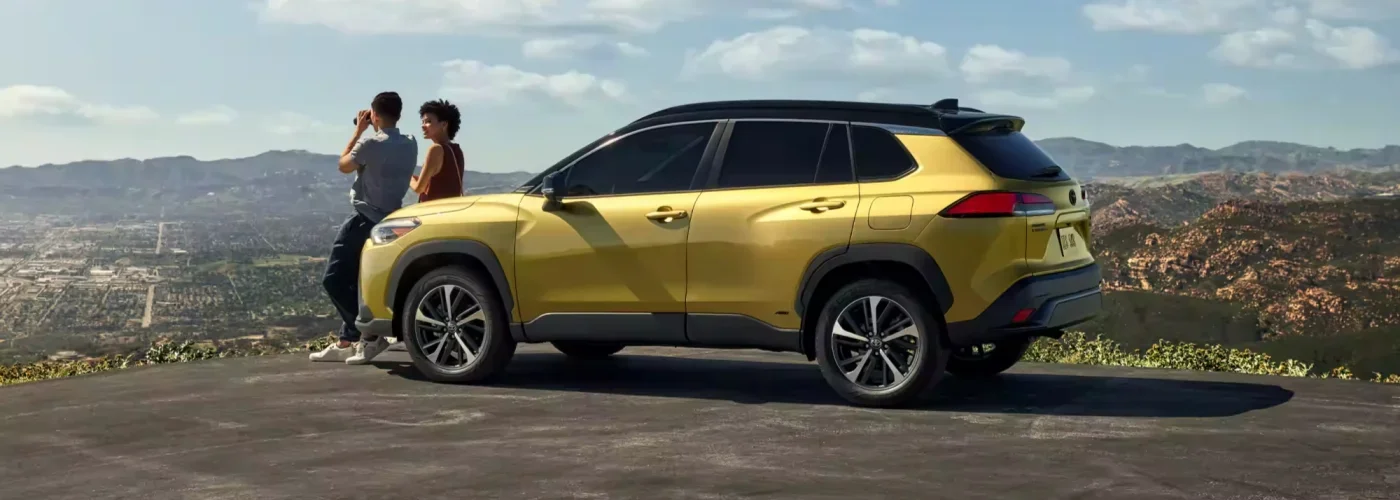 Un coche amarillo con dos personas a bordo contemplando la ciudad desde un mirador panorámico.