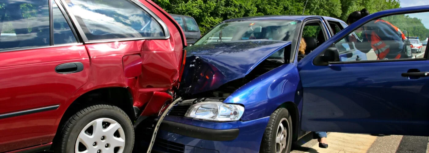 Un coche rojo destrozado quedó aplastado contra la parte delantera de un coche azul, con el capó levantado, tras una colisión por alcance.